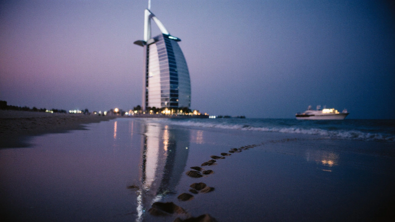 Low-angle reflection of Burj Al Arab in wet sand with footprints leading to the sea at twilight.